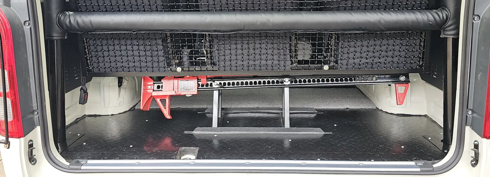 Chequered-plate floor, cargo barrier and a mounted high-lift jack in the back of a Hiace