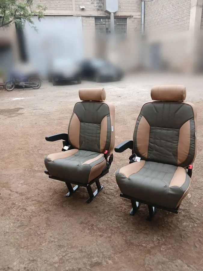 A pair of tan and olive Land Cruiser captain seats in the workshop yard