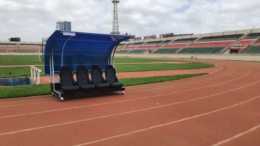Covered dugout with bucket seats beside a stadium running track