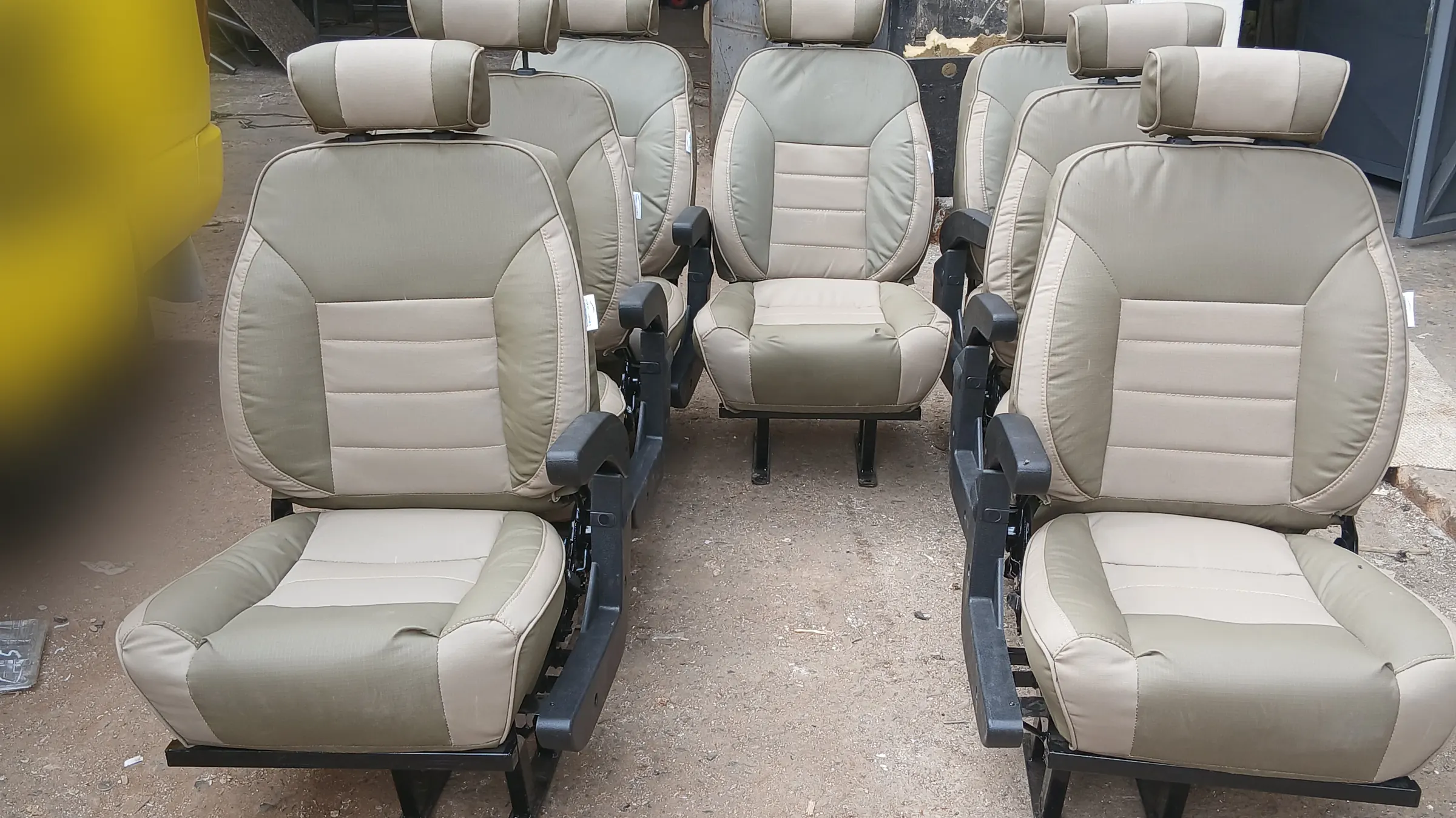 Beige two-tone Land Cruiser seats with armrests lined up in the workshop