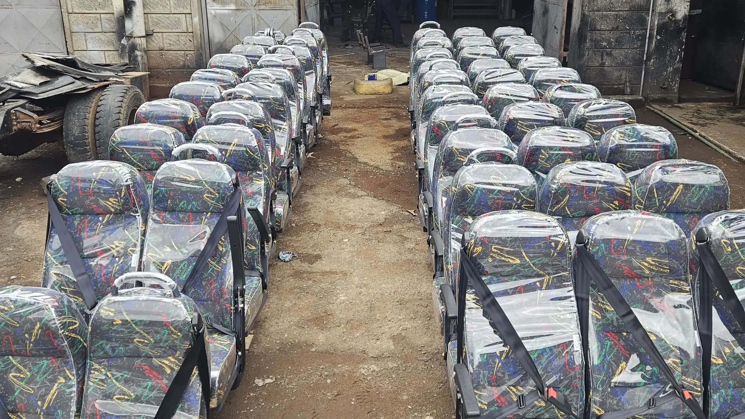 Rows of standard passenger seats with seat belts, ready in the workshop yard
