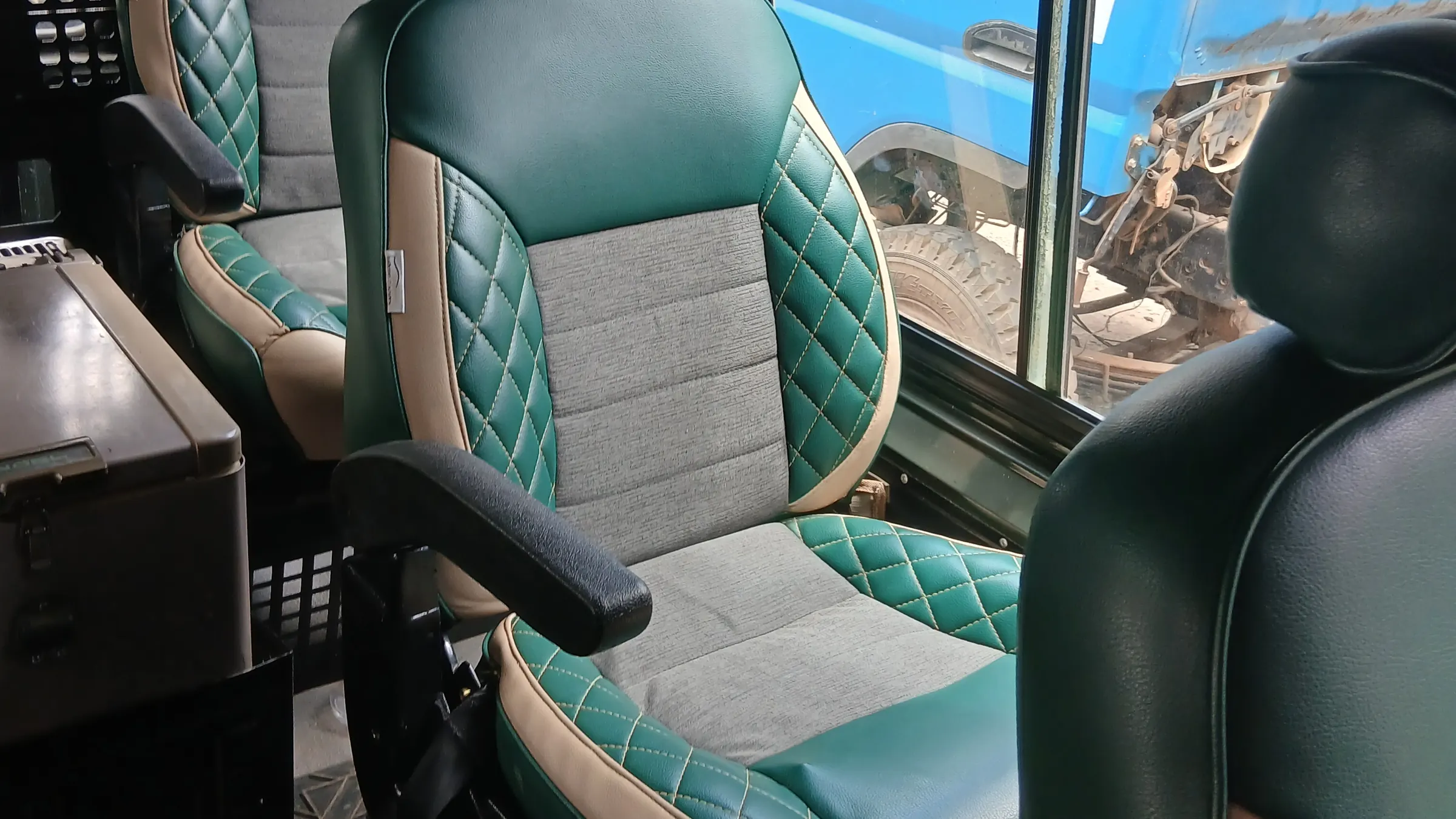 Green and grey diamond-stitch Land Cruiser seats with tan piping, fitted in a cabin