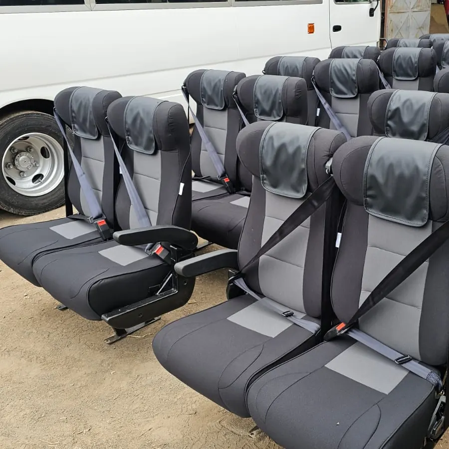 Grey and black executive seats with seat belts lined up in the workshop yard