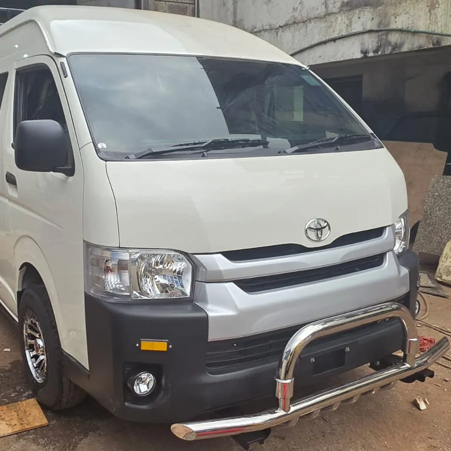 White high-roof Toyota Hiace with a chrome front bumper guard and roof rack